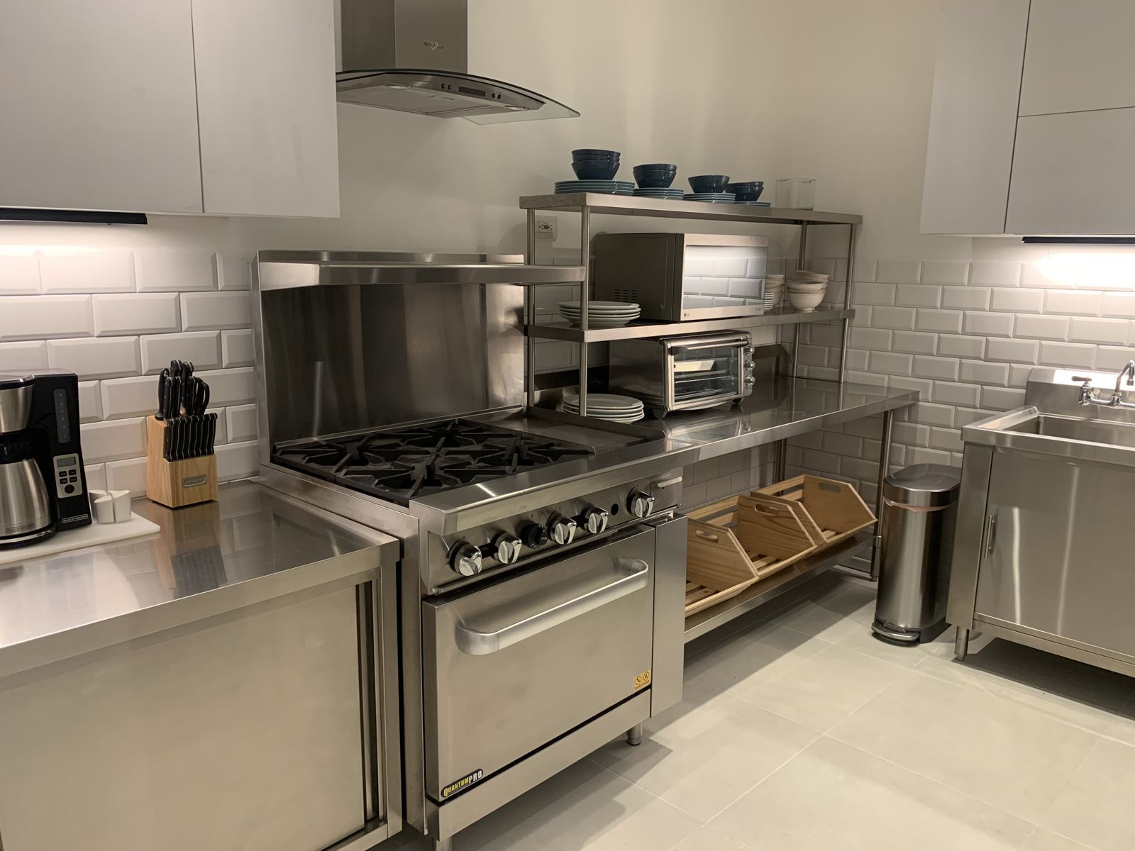 Stainless steel chef’s kitchen with a gas range and open shelving